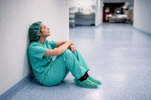 Physician sitting alone in hospital hallway feeling stuck in medicine and experiencing career dissatisfaction